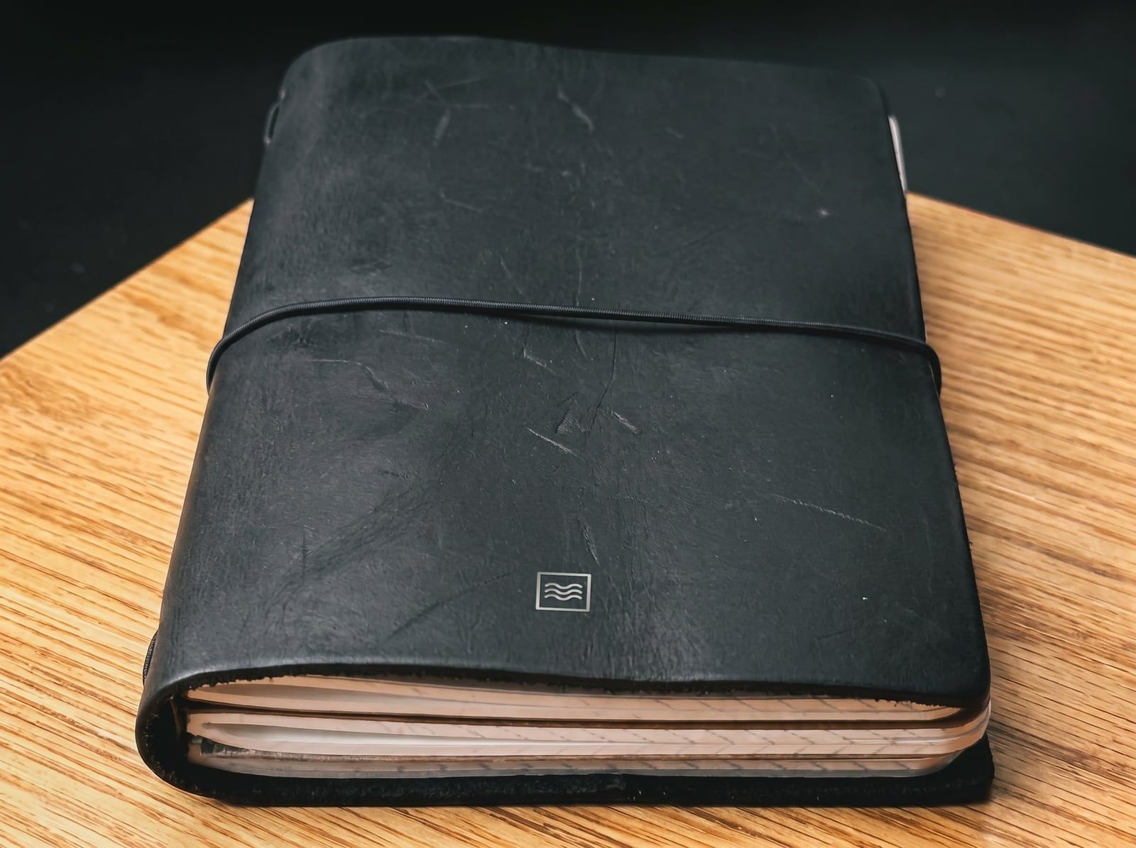 The System: an A6 cover in black leather with the Tidemark monogram in silver foil, an elastic cord and a stack of inserts.